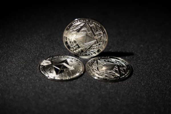 Close-up of three Ethereum coins on a dark background, showcasing digital currency themes.