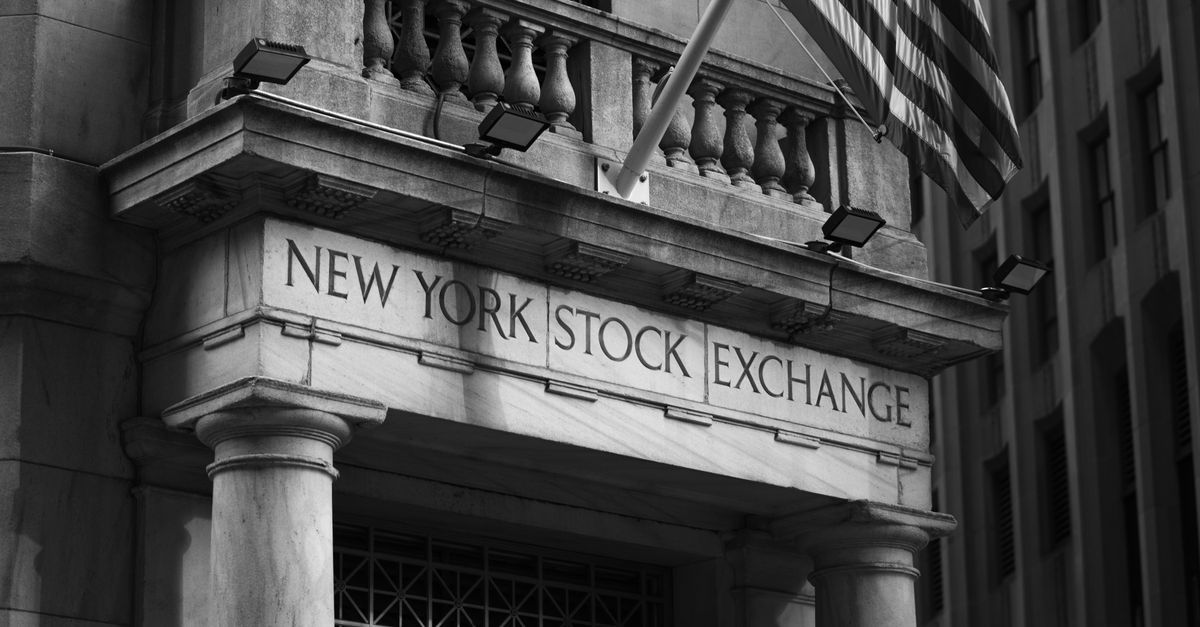 Black and white photo of the New York Stock Exchange facade with USA flag.