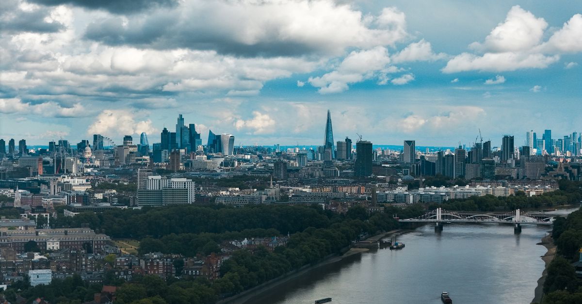 Wide-angle view of London's modern skyline and River Thames under a dramatic sky.