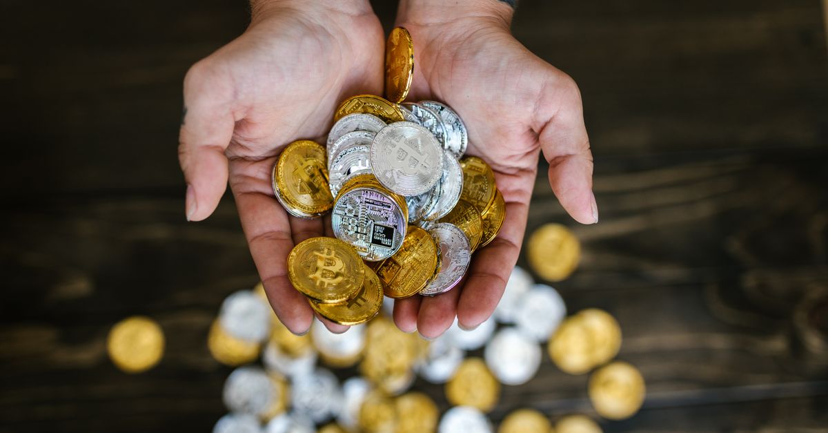 Close-up of hands holding gold and silver cryptocurrency coins symbolizing wealth and finance.