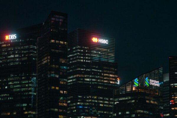 Illuminated city skyscrapers of major banks in Singapore's financial district at night.