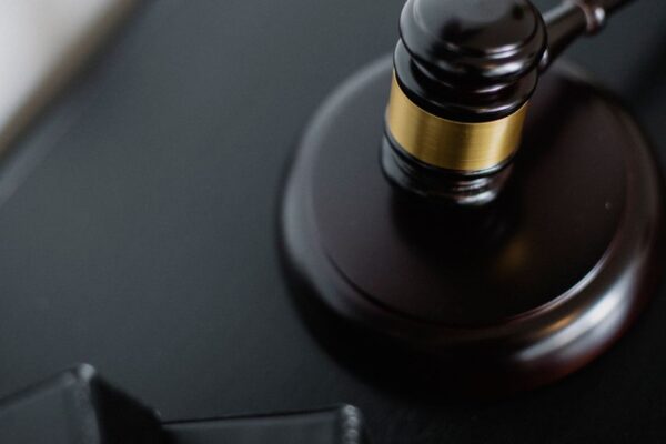 From above of wooden gavel on round surface near folders on table in courtroom