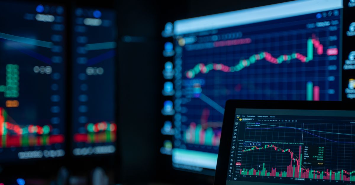 Monitors displaying stock market charts in a dimly lit room, perfect for finance and trading themes.