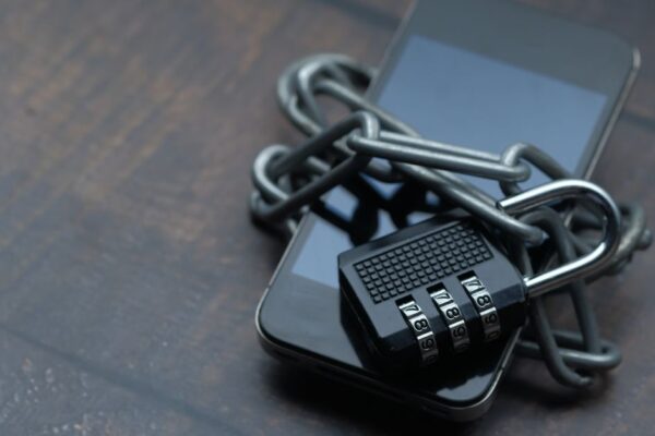 Close-up of a smartphone wrapped in a chain with a padlock, symbolizing strong security.