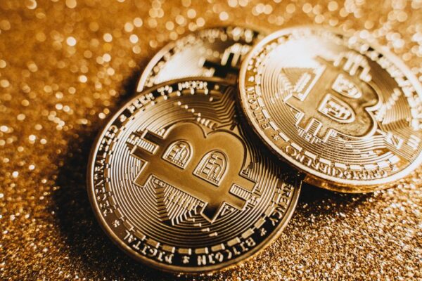 Close-up of shiny bitcoins on a gold glitter background, symbolizing cryptocurrency wealth.