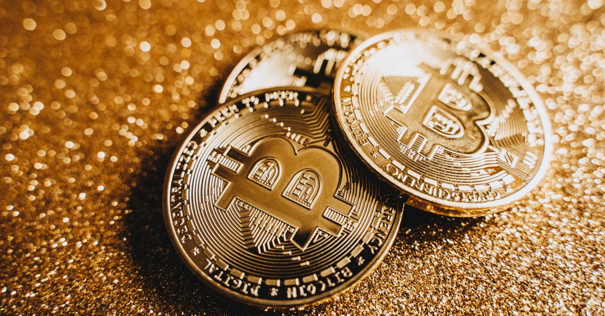 Close-up of shiny bitcoins on a gold glitter background, symbolizing cryptocurrency wealth.