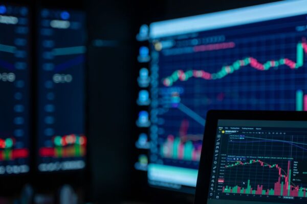 Monitors displaying stock market charts in a dimly lit room, perfect for finance and trading themes.