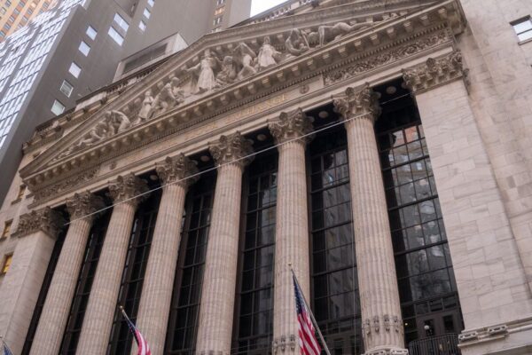 Close-up view of the iconic New York Stock Exchange building with American flags, located in Wall Street, NYC.