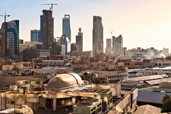 Skyline of Riyadh, Saudi Arabia featuring modern skyscrapers and construction cranes at sunset.