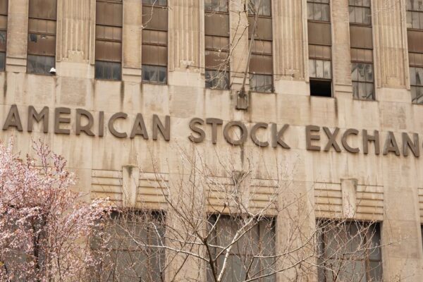 Facade of the American Stock Exchange Building in New York City during spring with blooming trees.