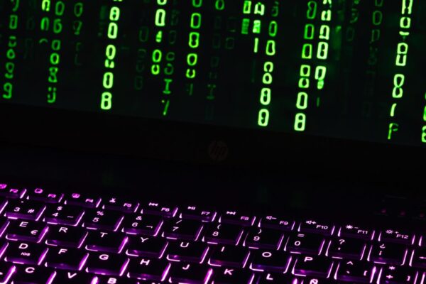 Illuminated laptop keyboard with Matrix-style green code cascading down screen.