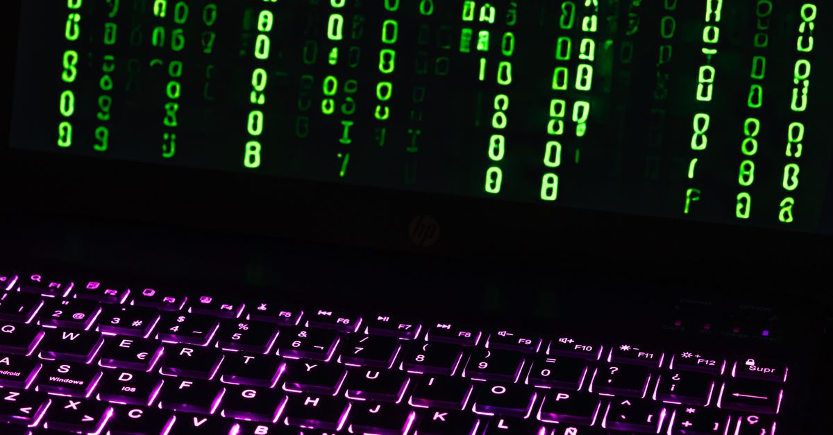 Illuminated laptop keyboard with Matrix-style green code cascading down screen.