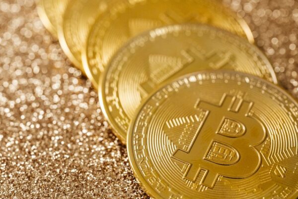 Close-up of golden Bitcoin coins on a shimmering glitter background, symbolizing digital currency's allure.