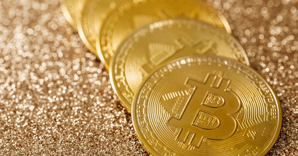 Close-up of golden Bitcoin coins on a shimmering glitter background, symbolizing digital currency's allure.