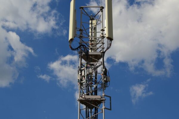 A tall cellular communication tower against a vivid blue sky, symbolizing modern technology.